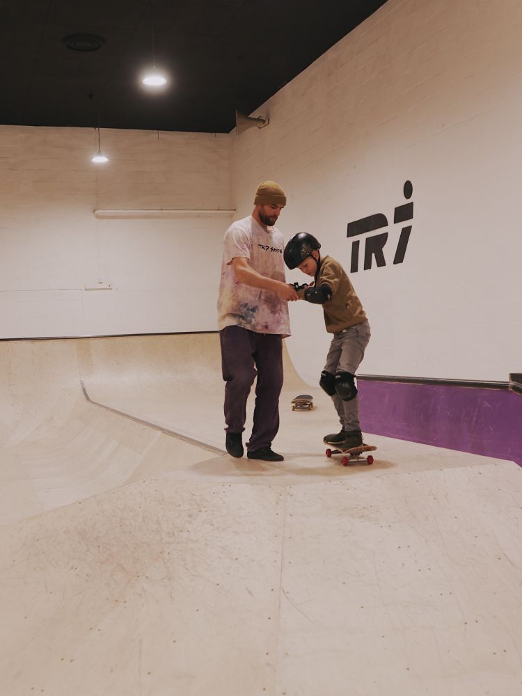 young boy being helped by an instructor on a skateboard lesson experience day