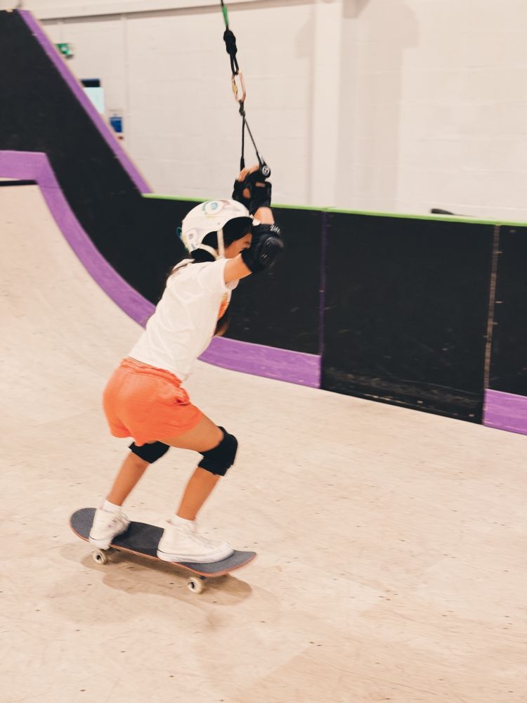 young girl using the rope system to go down the ramp on a skateboard lesson experience day