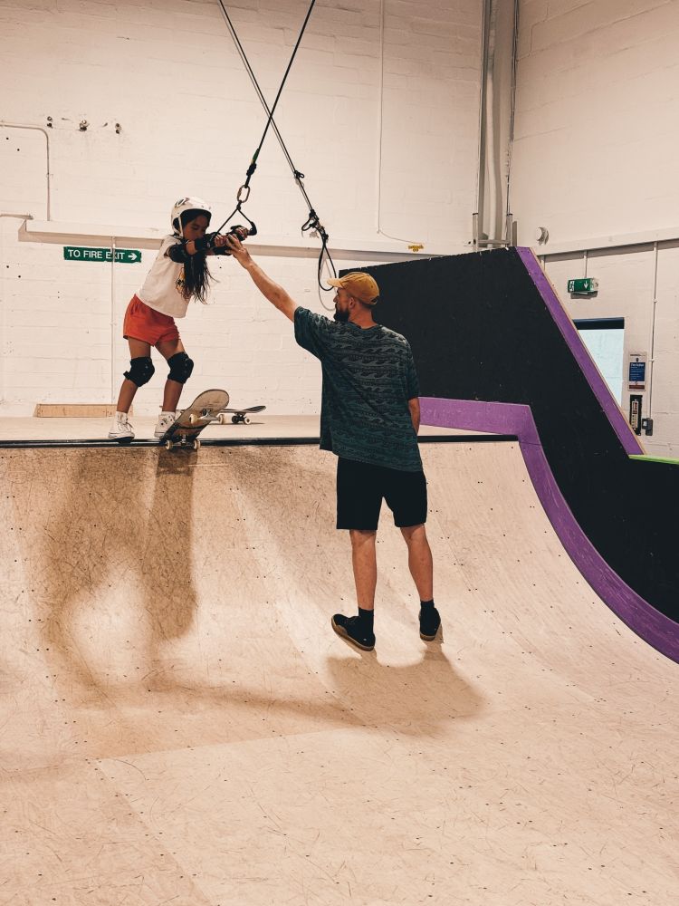 young girl using rope system on ramp on a skateboard lesson experience day