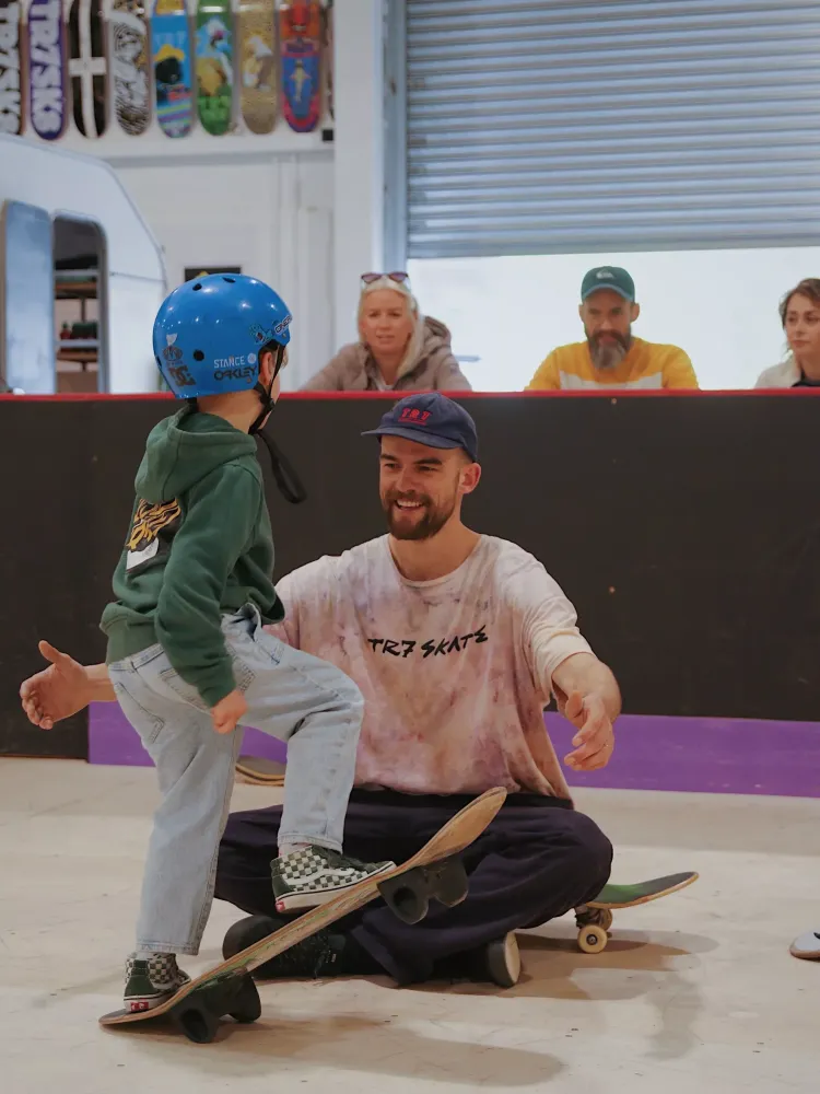 young child on a skateboard lesson experience day watched by parents