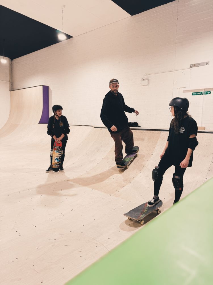 two people watching instructor on a skateboard lesson experience