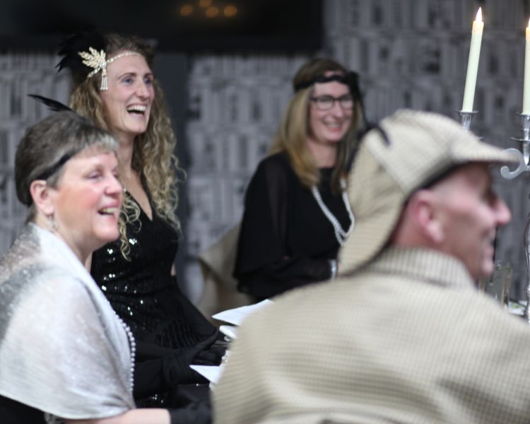 murder mystery dinner guests dressed in costume sitting at table