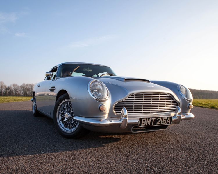 a silver db5 aston martin on the side of a race track as part of a driving experience day