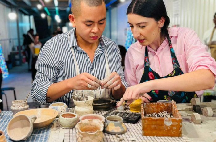 two people sitting at a bench working on pottery painting on a pottery experience in london