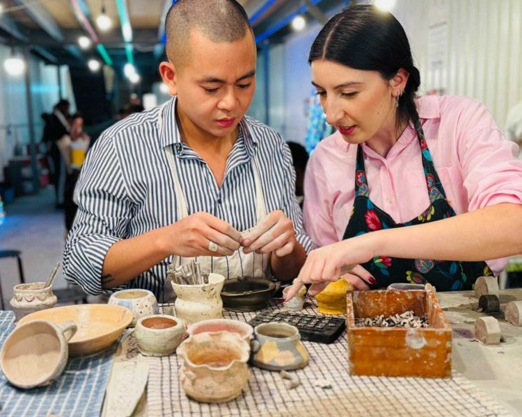 two people sitting at a bench working on pottery painting on a pottery experience in london