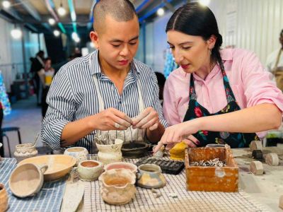 two people sitting at a bench working on pottery painting on a pottery experience in london