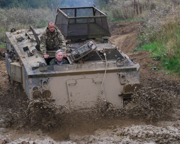 a military tank being driven through a muddy puddle on a tank driving experience day