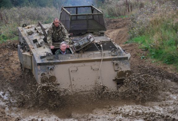 a military tank being driven through a muddy puddle on a tank driving experience day