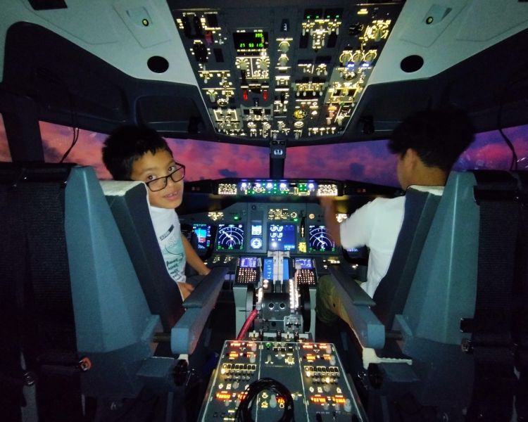 to young boys in the cockpit of a Boeing 737 - 800NG on a simulator experience