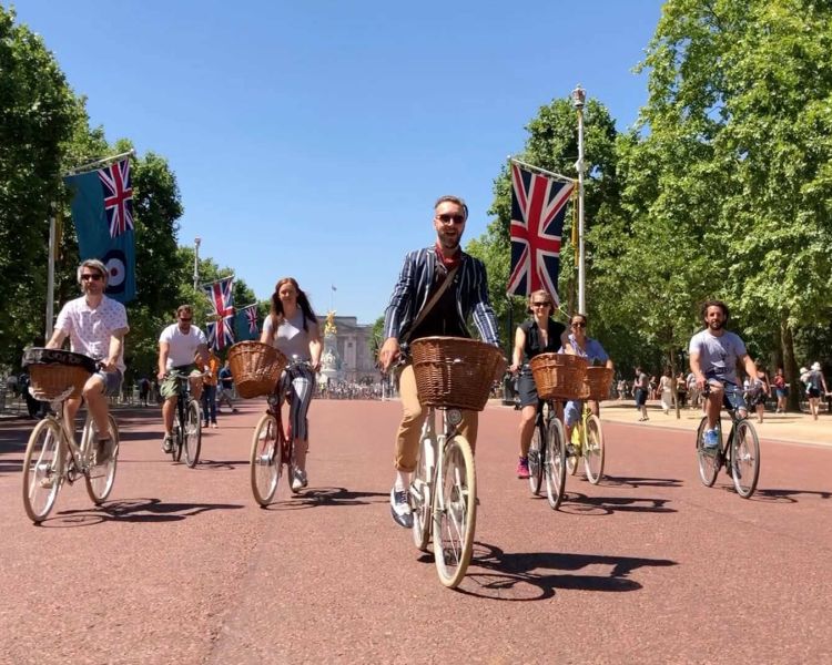 group of people riding vintage bicycles up the mall past buckingham palace on a bike sightseeing tour