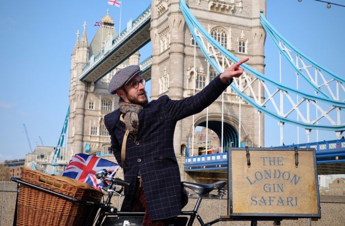 man with vintage bicycle in front of tower bridge on a london gin bike tour