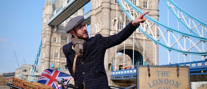 man with vintage bicycle in front of tower bridge on a london gin bike tour