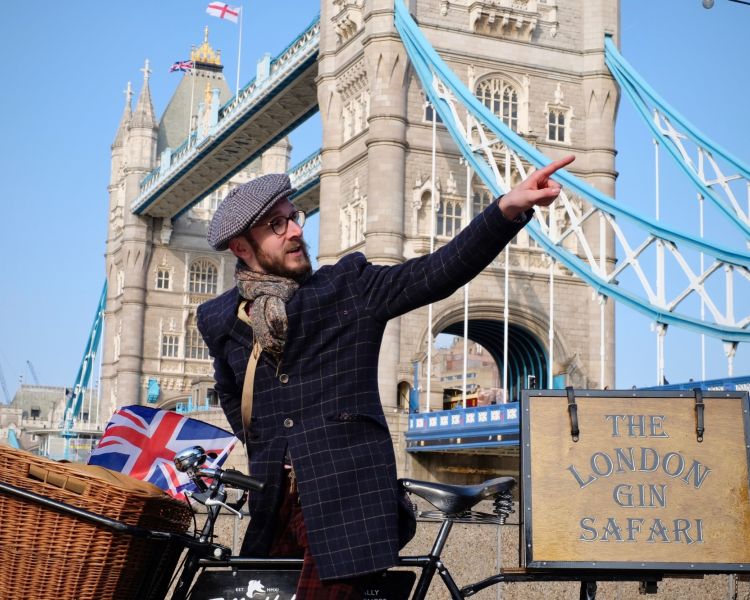 man with vintage bicycle in front of tower bridge on a london gin bike tour