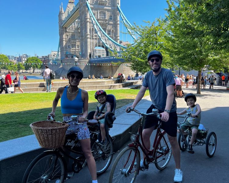 a family posing for a photo in front of tower bridge on a london bike tour
