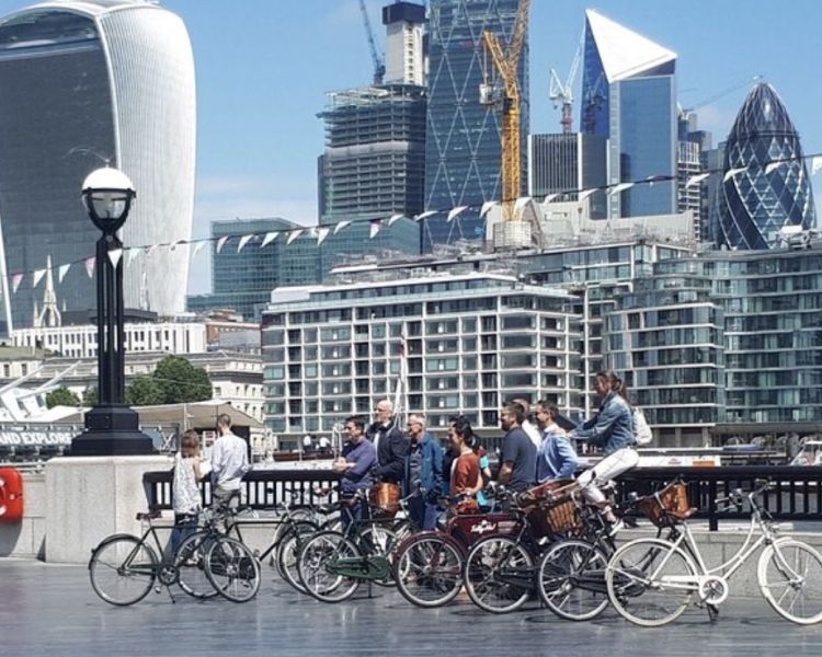 a group of people posing for a photo alongside the river thames with the city of london in background