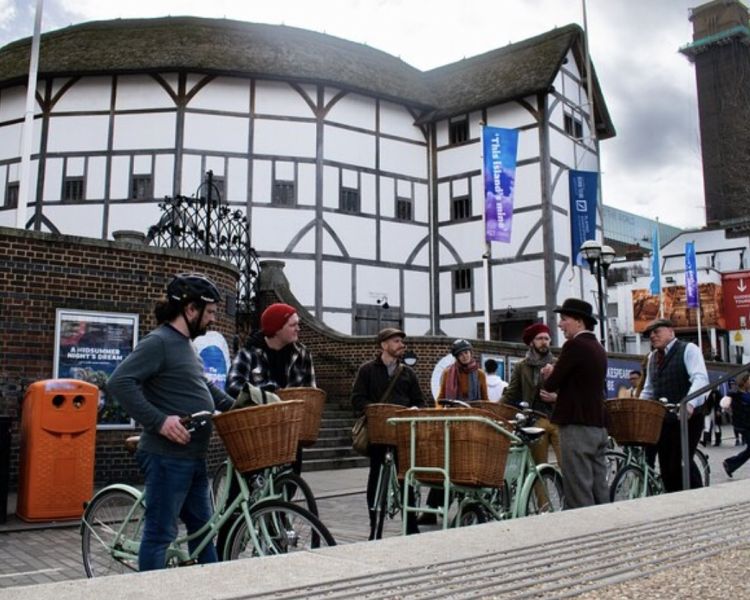 a tour group stopped in front of a timber building on a london bike tour