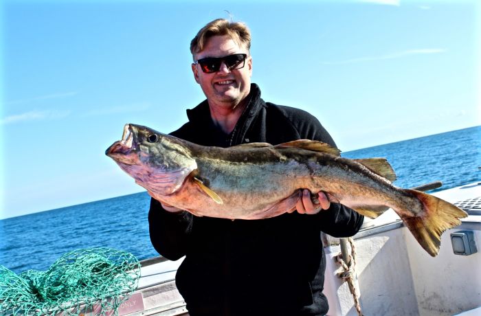 a man holding a fish caught on a deep sea fishing trip off the east sussex coast