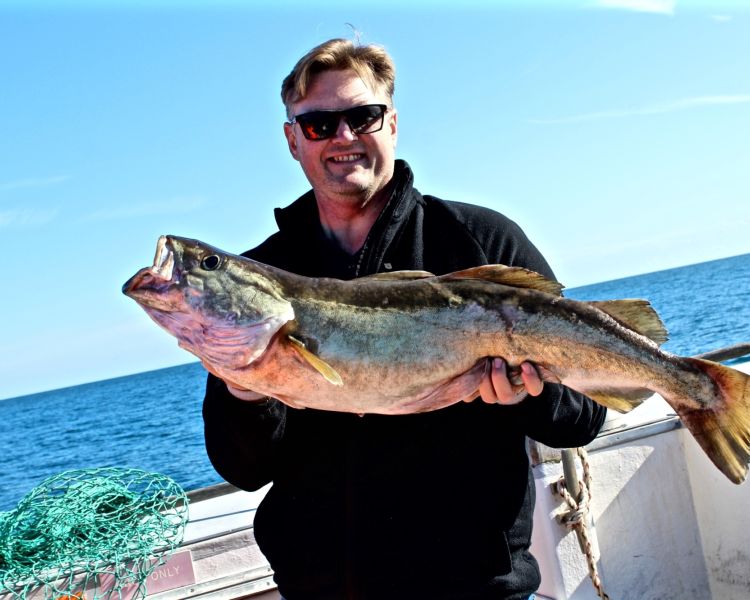 a man holding a fish caught on a deep sea fishing trip off the east sussex coast