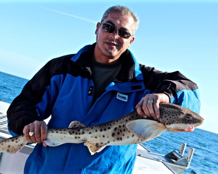 a man holding a fish caught on a deep sea fishing trip off the east sussex coast