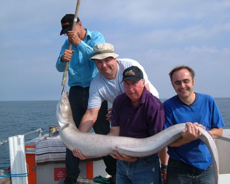 three men holding an eel caught on a deep sea fishing trip off the east sussex coast