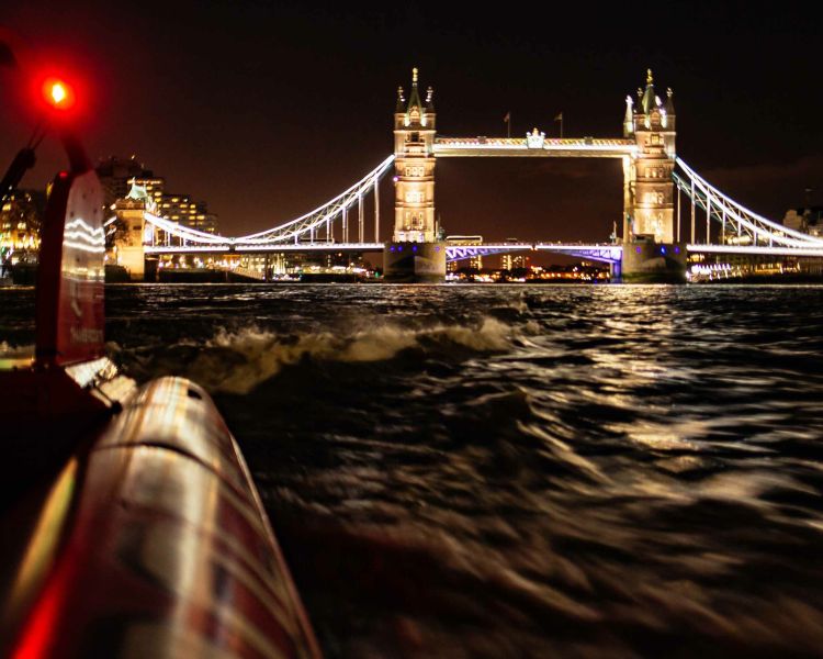 passengers enjoying a thames rocket speedboat experience in london at night with tower bridge lit up