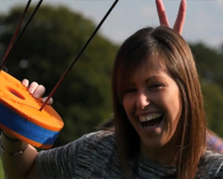 woman celebrating holding the foam target after a game of skybow