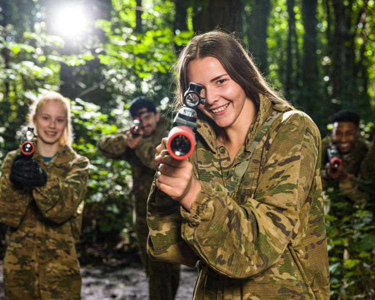 group of young people dressed in camouflage gear ready for forest laser tag