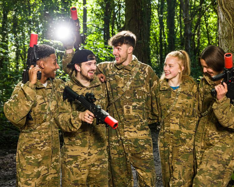 group of young people dressed in camouflage gear ready for forest laser tag