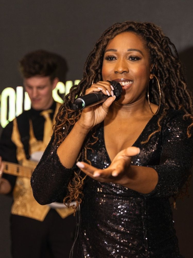 a woman singing on stage at a motown dining experience in london