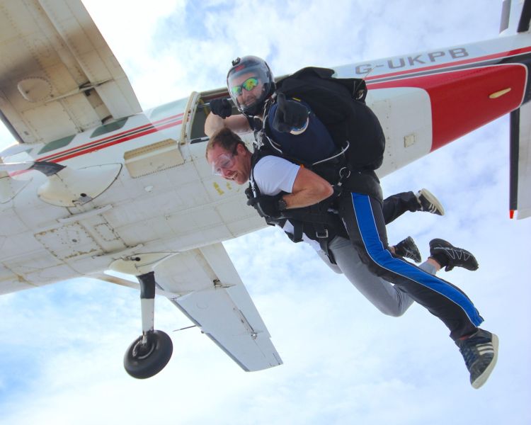 a man on a tandem skydiving experience having just jumped out of the plane