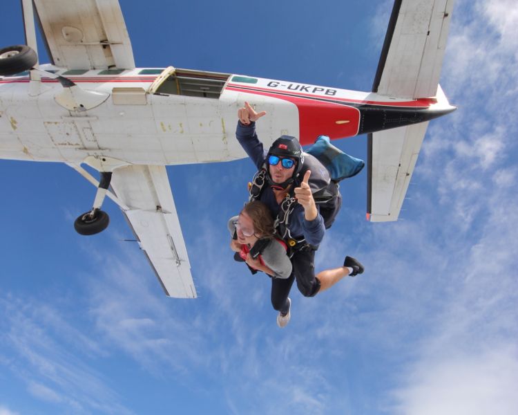 a woman on a tandem skydiving experience having just jumped out of the plane