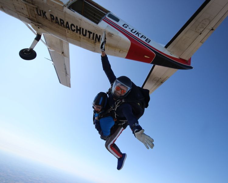 a man on a tandem skydiving experience having just jumped out of the plane