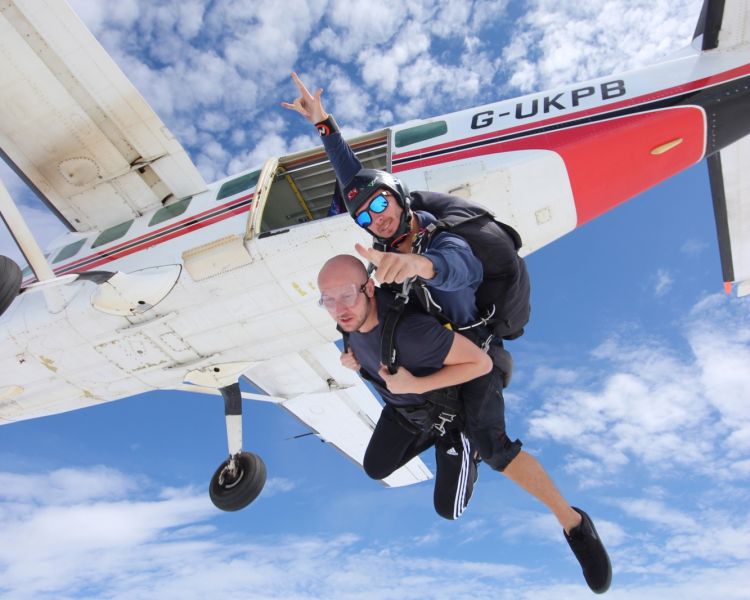 a man on a tandem skydiving experience having just jumped out of the plane