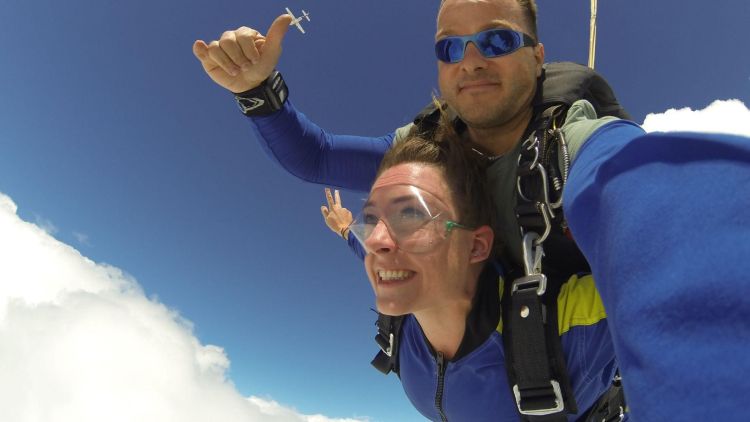 a woman on a tandem skydive during freefall against a blue sky