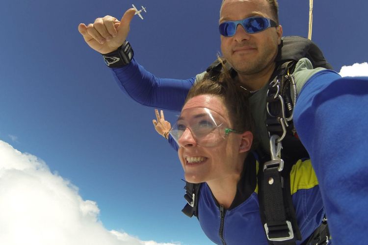 a woman on a tandem skydive during freefall against a blue sky