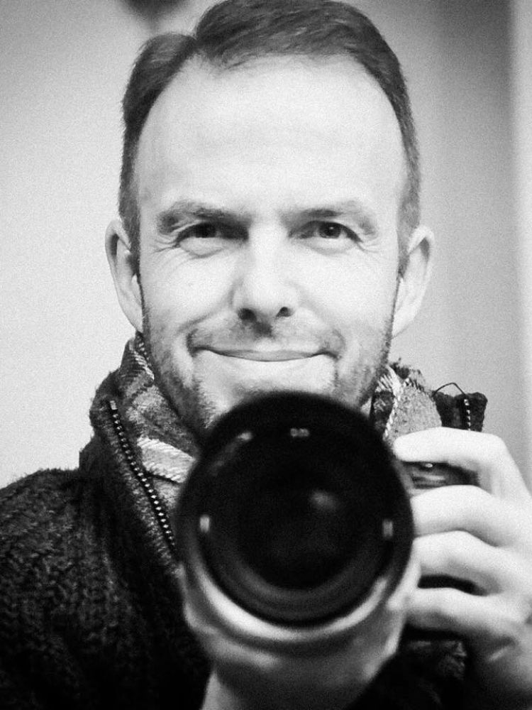 a black and white photo of professional photographer warren garrett holding a camera