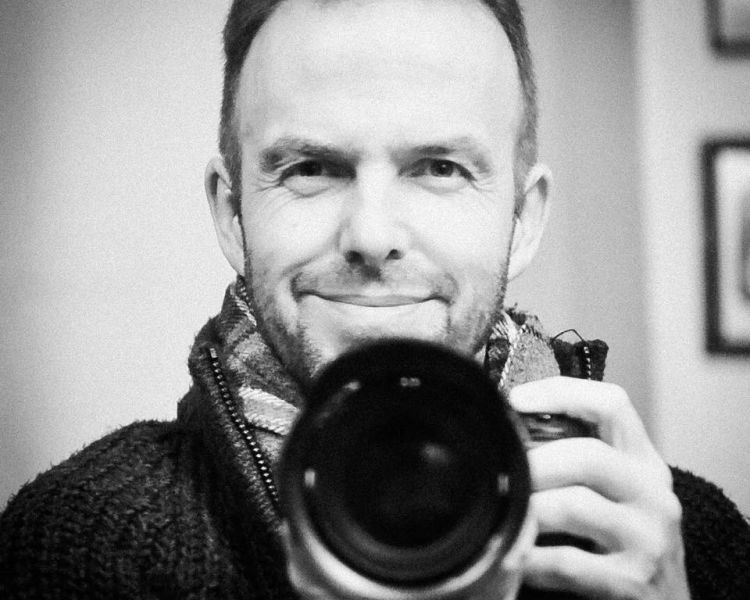 a black and white photo of professional photographer warren garrett holding a camera