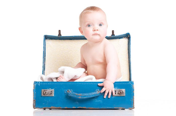 baby sitting in a blue suitcase on a photoshoot