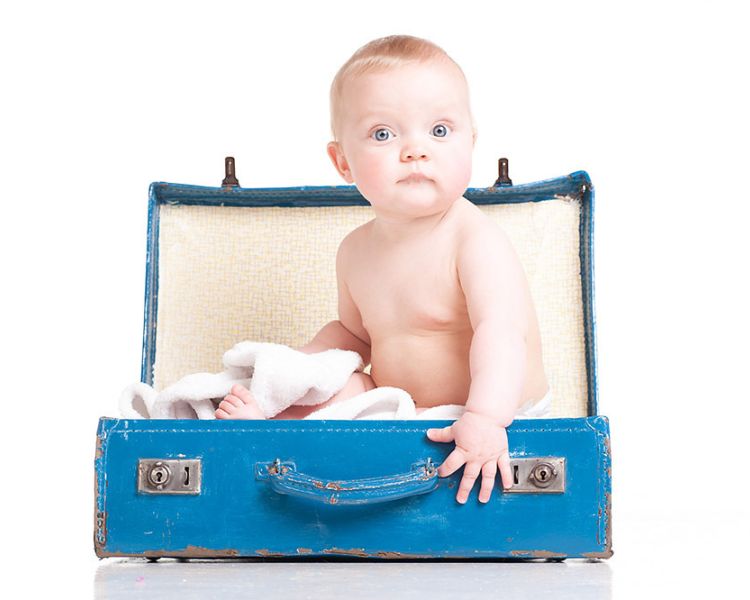 baby sitting in a blue suitcase on a photoshoot