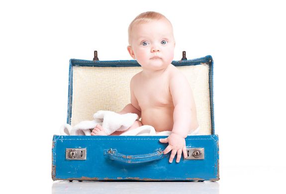 baby sitting in a blue suitcase on a photoshoot