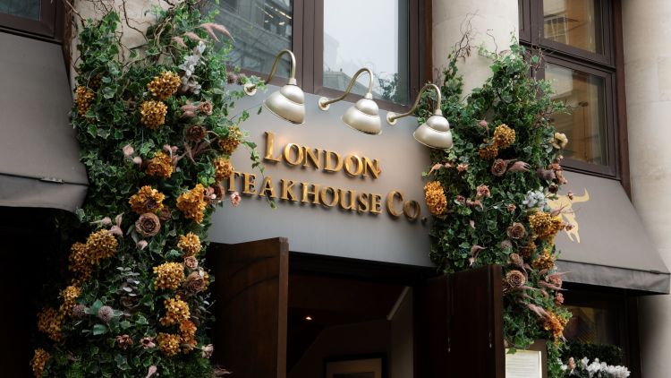 the front of marco pierre white's london steakhouse company with flowers around the doorway