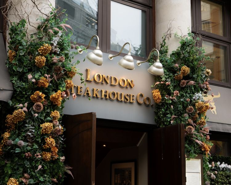 the front of marco pierre white's london steakhouse company with flowers around the doorway