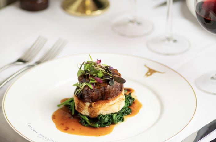 a meal of steak on top of mashed potato and greens at marco pierre white's london steakhouse company