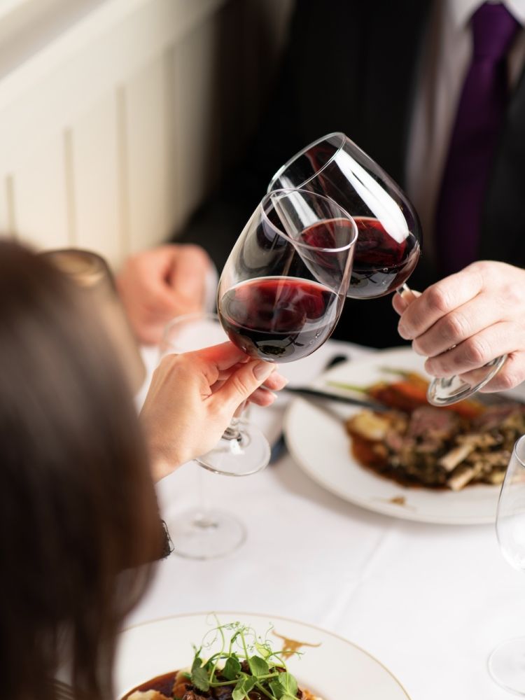 two people enjoying a meal with red wine at marco pierre white's london steakhouse company