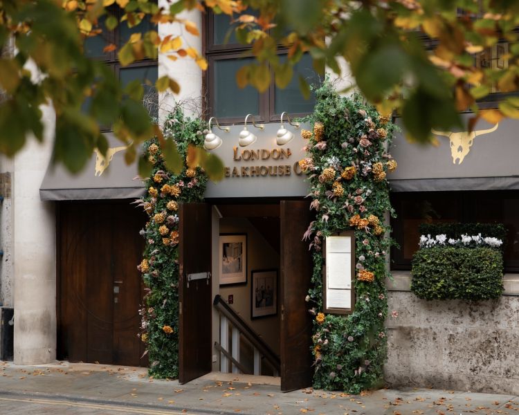 the front of the marco pierre white's london steakhouse company with flowers around the doorway