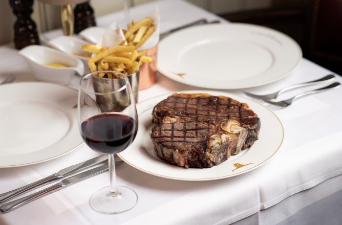 a steak meal with fries on the side and a glass of wine at marco pierre white's london steakhouse company