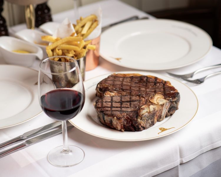 a steak meal with fries on the side and a glass of wine at marco pierre white's london steakhouse company