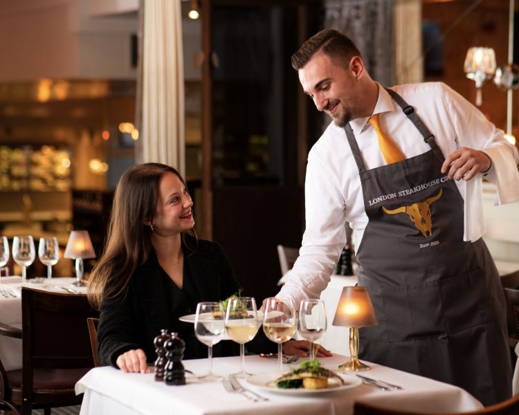 a woman being served a meal at marco pierre white's london steakhouse company