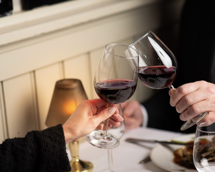 two people clinking wine glasses sharing a meal at marco pierre white's london steakhouse company