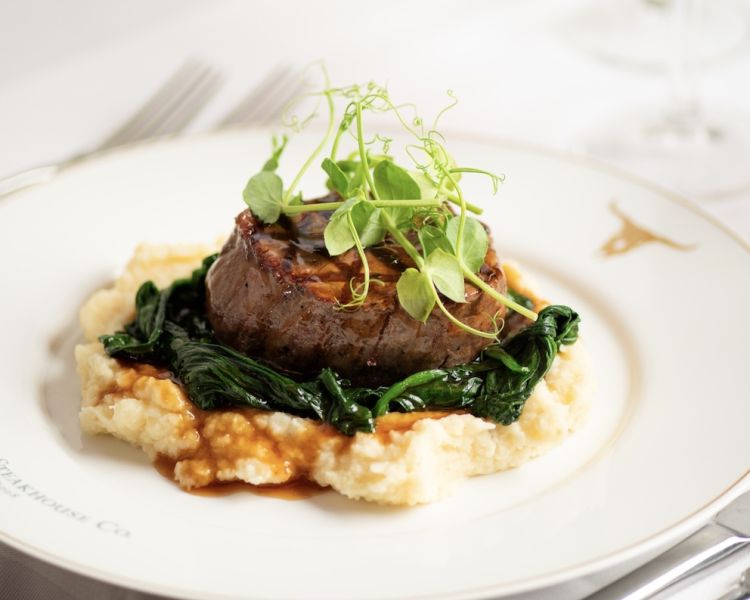 a meal at marco pierre white's london steakhouse company of steak on a layer of mashed potato and vegetables
